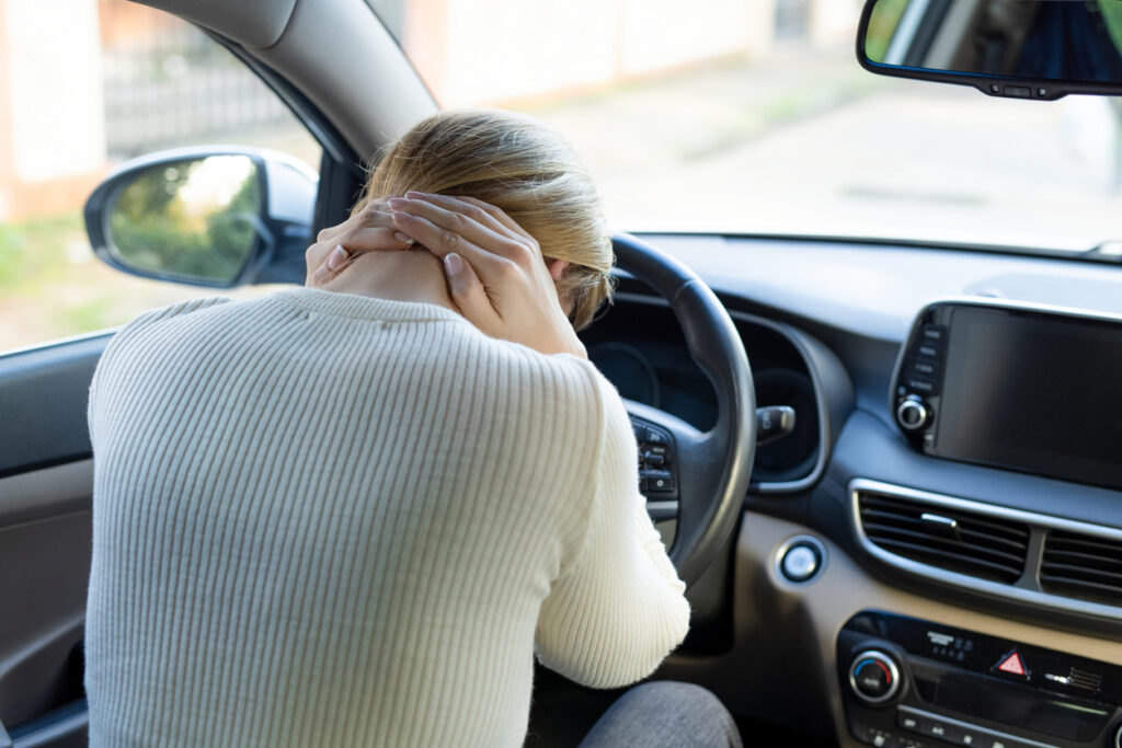 A woman clutching at her neck in pain to represent the issues that can come after car crashes