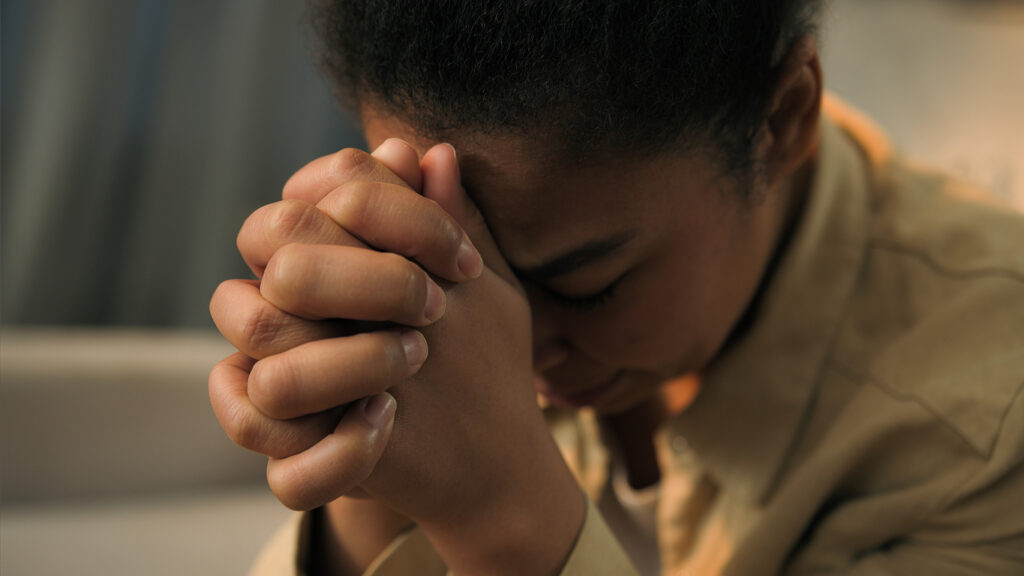 An upset woman clutching her fists in her hands to represent the trauma that can occur after car accidents